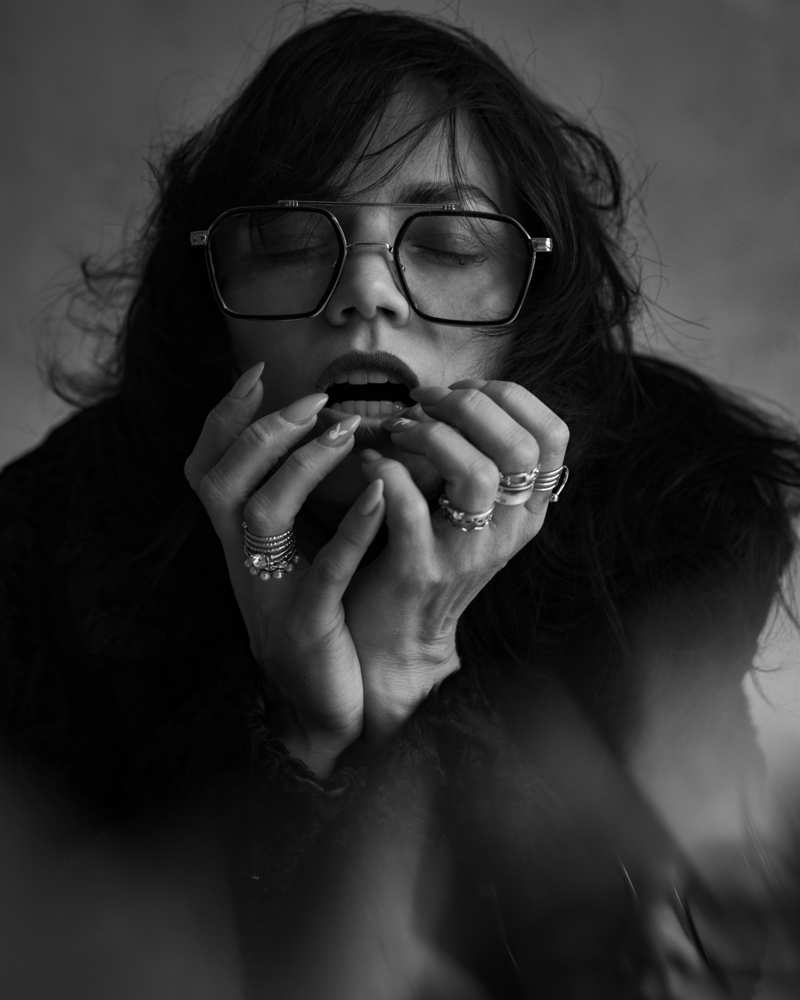 Alisa Pleskova in glasses, hands at her lips, black and white portrait